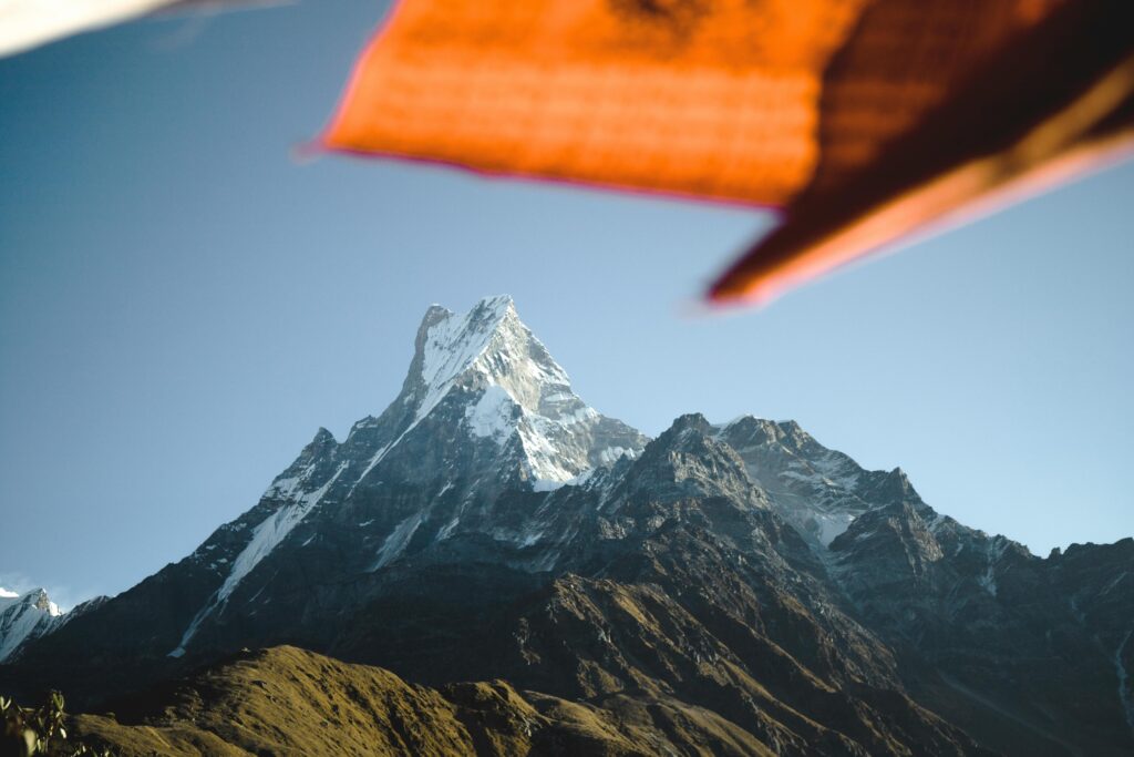 Stunning view of Machapuchare peak in the Himalayan range, Nepal, with vibrant prayer flags in the foreground.